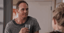 a man is holding a fork and a glass in front of a netflix sign
