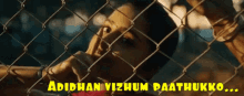 a woman behind a chain link fence with the words " adidhan vizhum paattukko "