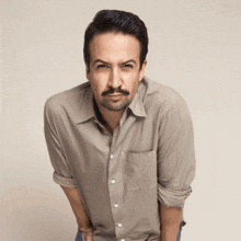 a man with a beard and mustache is wearing a grey shirt