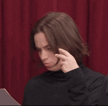 a man with long hair wearing a black turtleneck sweater
