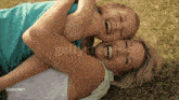 a woman and child are laying on the grass and laughing together