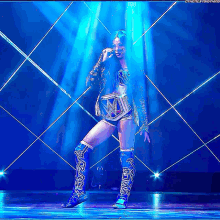 a woman in a wrestling outfit is standing on a stage in front of a blue light .