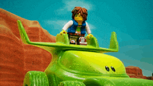 a lego figure is sitting on top of a green toy car