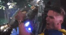 a man in a yellow and blue shirt is holding a large trophy in his mouth