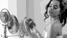 a woman is applying perfume in front of a mirror .