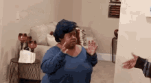a woman in a blue sweater is standing in a living room .