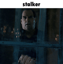 a picture of a man looking out a window with the word stalker above him