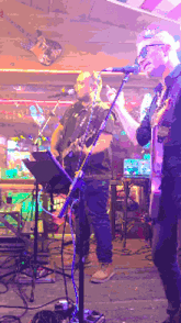 a man singing into a microphone while another man plays guitar