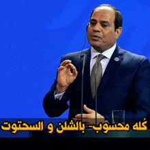 a man in a suit and tie is speaking into a microphone with a blue background