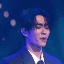a man in a suit and tie is brushing his hair while wearing ear buds .