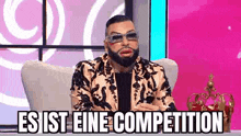 a man with a beard and sunglasses is sitting in a chair with the words `` es ist eine competition '' .