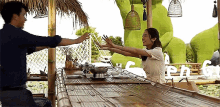 a man and a woman are sitting at a table with their hands outstretched .