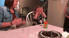 a little girl is sitting at a table with a birthday cake and candles on it .