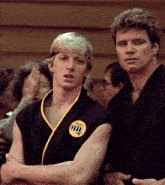 a man wearing a black karate uniform has a yellow patch on his chest that says karate