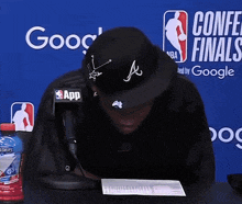 a man sitting in front of a conference finals banner