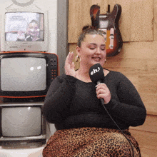 a woman singing into a microphone with eh written on it