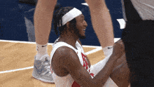 a basketball player wearing a white headband is being helped by a referee