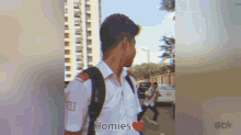 a man with a backpack is walking down a street with the words homies written on the bottom