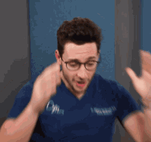 a blurry picture of a man wearing glasses and a blue shirt with the letter o on it