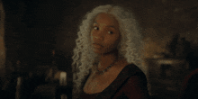 a woman with white curly hair and a necklace on her neck