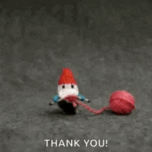 a stuffed gnome is holding a ball of yarn and saying `` thank you '' .