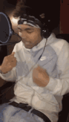 a man wearing headphones is sitting in front of a microphone .