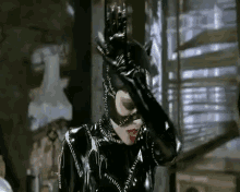 a woman in a catwoman costume is standing in a dark room .