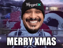 a man wearing a blizzard x beanie is smiling and wishing merry xmas