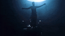 a silhouette of a man with his arms outstretched in front of a light .
