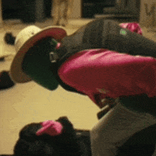 a person wearing a pink shirt and a green hat is kneeling down