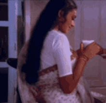 a woman in a white blouse is sitting at a table holding a cup of coffee .