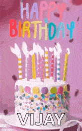 a birthday cake with candles and sprinkles on it is on a plate on a table .