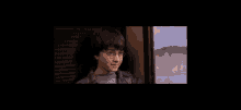 harry potter is holding his hand to his head while looking out a window