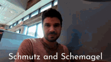 a man with a beard is sitting at a table with the words schmutz and schmagel written on the bottom