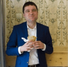 a man in a blue suit is eating a sandwich