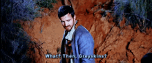 a man in a suit and tie is standing in the dirt and says what then greyskins ?