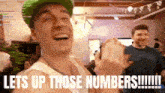 a man in a green hat laughs with the words lets up those numbers