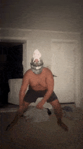 a shirtless man wearing a mask and glasses is dancing in a dark room