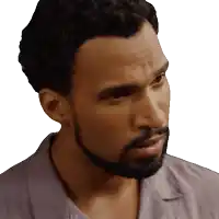 a man with a beard wearing a grey shirt looks to the side