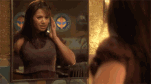a woman is looking at herself in a mirror while talking on a cell phone