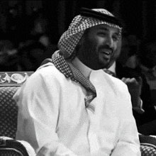 a black and white photo of a man wearing a white shirt and scarf