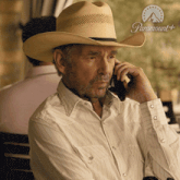 a man wearing a cowboy hat talking on a cell phone