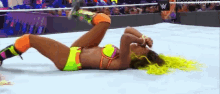 a woman in a bikini is laying on the floor in a wrestling match .