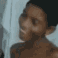 a blurred image of a shirtless boy smiling .