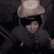 a man wearing a cowboy hat is sitting in front of a microphone in a dark room .