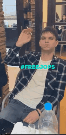 a man in a plaid shirt is smoking a cigarette with the hashtag #freejops behind him