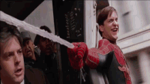 a man in a spiderman costume is holding a spider web in his hand