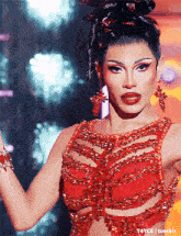 a woman is wearing a red dress with a bun in her hair and earrings ..