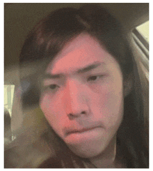 a man with long hair is sitting in a car making a funny face