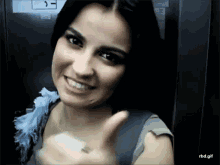 a woman is smiling and giving a thumbs up in an elevator with a sticker on the wall that says j